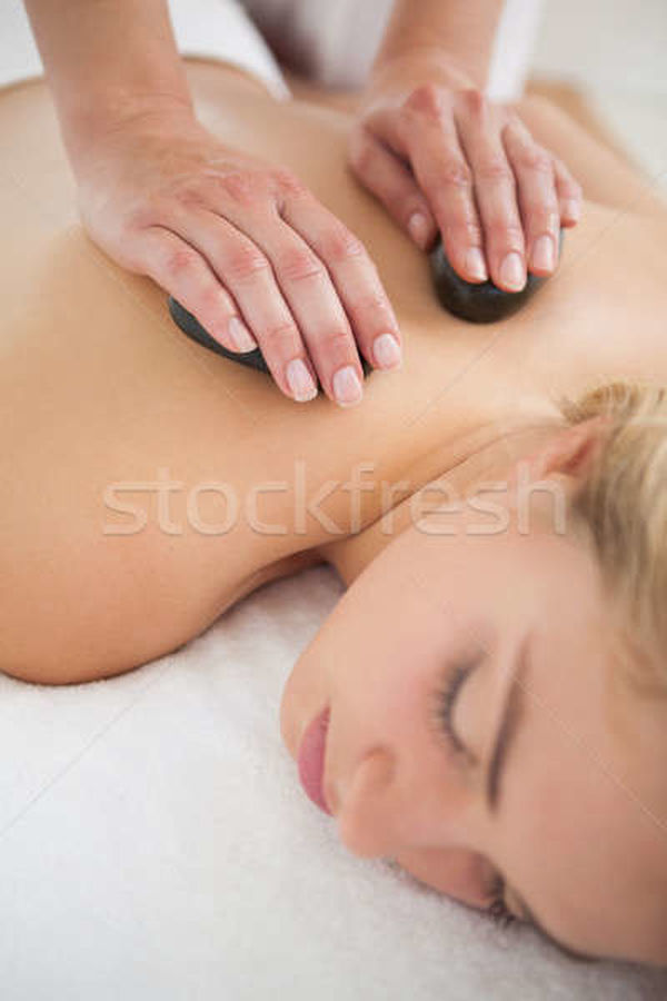 Beautiful blonde enjoying a hot stone massage stock photo Â©