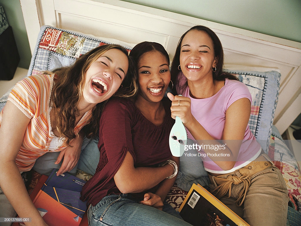 Three Teenage Girls On Bed Laughing Elevated View Stock Phot